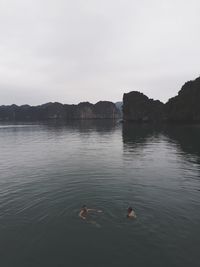People swimming in lake against sky