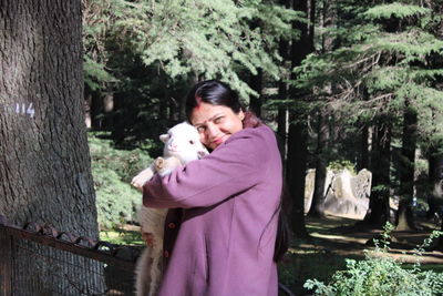 Woman with dog against trees