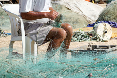 Low section of man working on fishing net