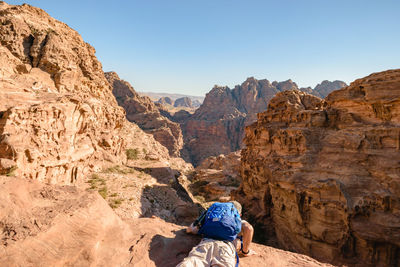 Rear view of person on rock formation against clear sky