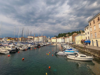 Sailboats moored in harbor against buildings in city