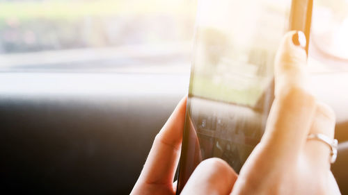 Cropped image of woman using digital tablet in car