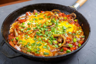 Shakshuka hot with herbs in a frying pan on a gray table. horizontal photo