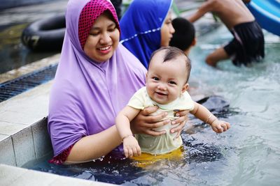 Smiling woman with daughter and sister sitting in pool