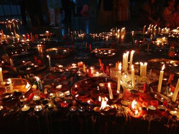 Close-up of illuminated candles on table in temple at night