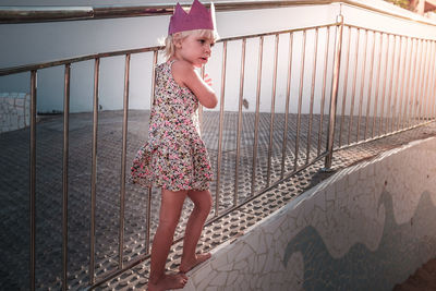 Girl standing on railing against water
