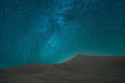 Scenic view of sand dunes in desert against sky at night