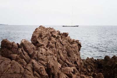 Rock formations on shore against clear sky