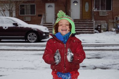 Portrait of cheerful boy wearing warm clothing standing on snow