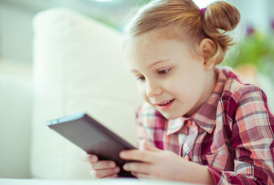 Close-up of smiling girl using mobile phone