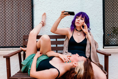 Two young women in the backyard in summer taking pictures with their mobile phones.