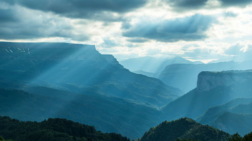 The rays of the setting sun break through the clouds and flow beautifully down the mountain slopes