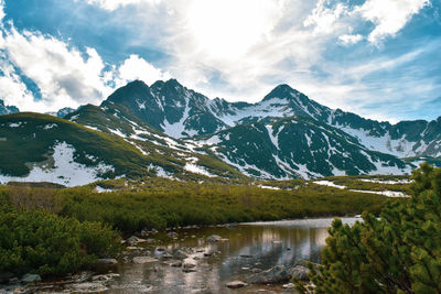 Scenic view of lake by snowcapped mountains against sky