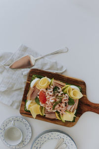 Swedish sandwich cake with shrimps, cheese, ham and eggs on wooden board at table