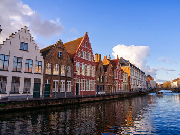 Buildings by river against sky