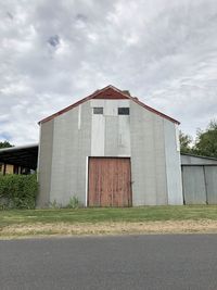 Barn on field by building against sky