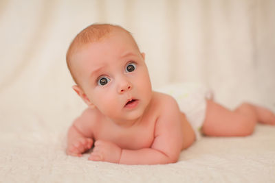 Portrait of cute baby lying on bed