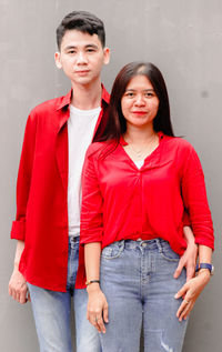 Portrait of smiling couple standing against wall