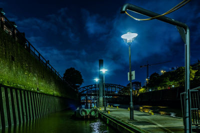 Illuminated bridge over canal against sky at night