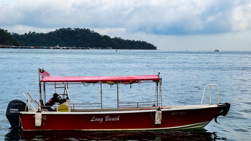 Fishing boat moored in sea against sky