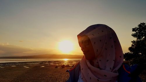 Young woman wearing hijab against sky during sunset