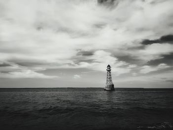 Lighthouse by sea against sky