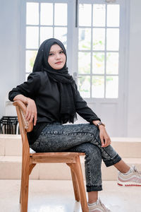 Portrait of young woman sitting on sofa at home