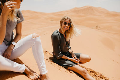 Young woman sitting on sand dune in desert