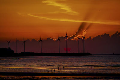 Silhouette cranes against sky during sunset