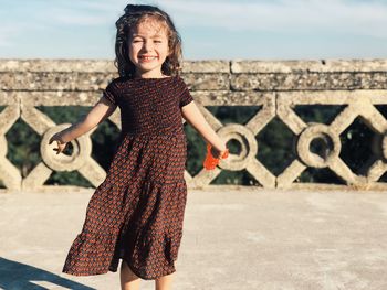 Portrait of smiling cute girl standing on footpath