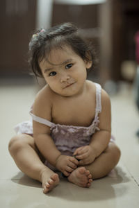 Portrait of cute baby girl sitting on floor