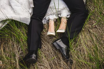 Low section of couple sitting on field