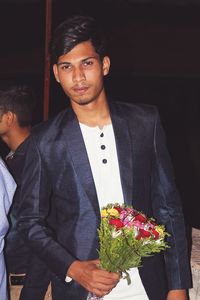 Portrait of young man holding bouquet