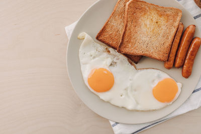 Breakfast set of fried eggs toasted bread sausages and tuna spread.