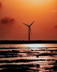 Silhouette of wind turbine against sky during sunset