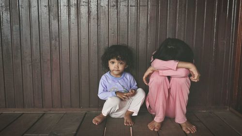 Full length of siblings sitting on wood