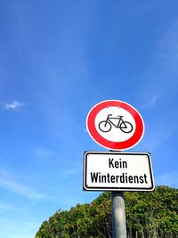 Low angle view of road sign against blue sky