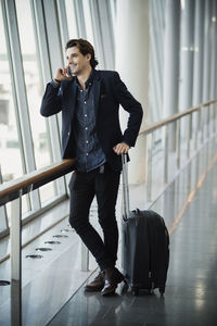 Happy businessman using smart phone at airport