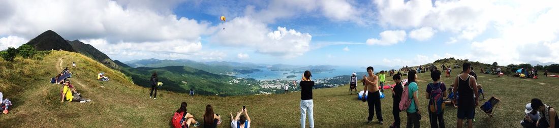Panoramic view of people on mountain against cloudy sky