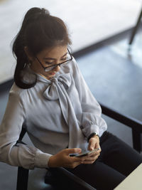 High angle view of businesswoman using mobile phone while sitting on chair