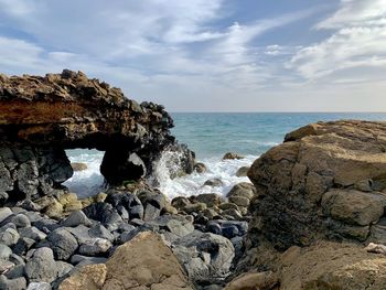 Scenic view of rocks on beach against sky