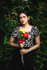 Portrait of a beautiful young woman standing against plants