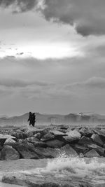 Man standing on rock against sky