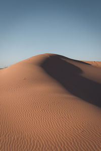 Sand dunes in desert against clear sky