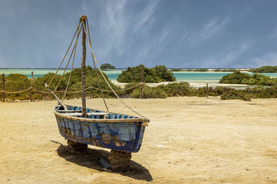 Boat moored on beach against sky