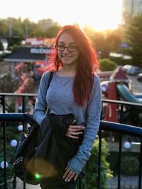 Portrait of smiling young woman standing against sky
