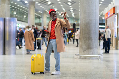 Smiling man waving while standing at airport