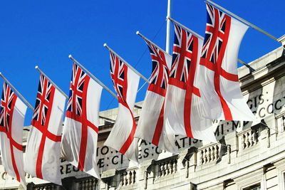 Low angle view of british flags against clear blue sky