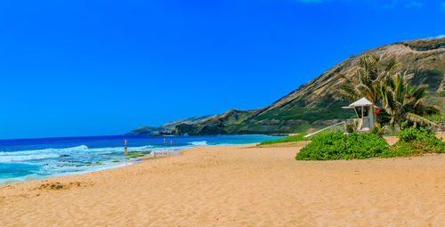 Scenic view of beach against clear blue sky