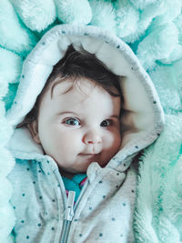 Portrait of cute baby lying on bed wrapped in blanket